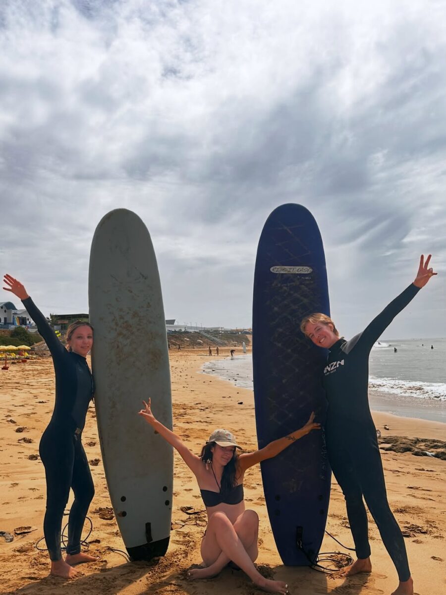 Friends posing with their surfboards on the beach