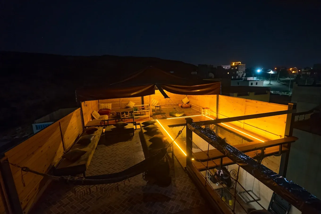 The rooftop lounge lit up at night, with the town lights behind