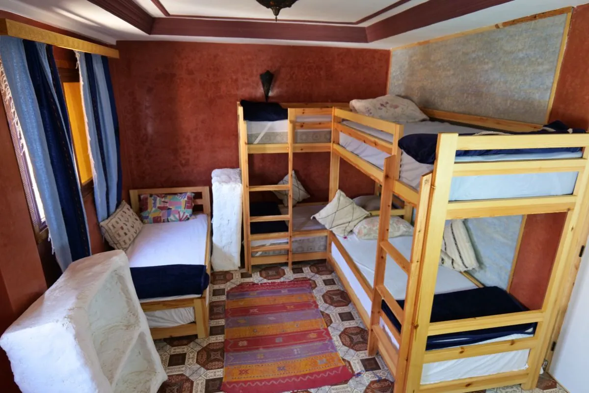 Mixed dorm with wooden bunks, red walls and a striped rug
